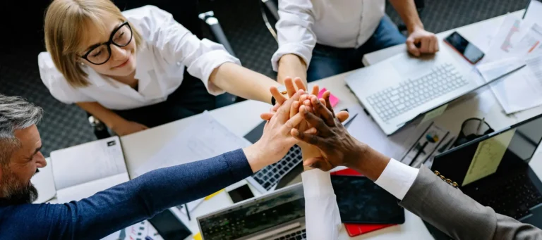 empresarios de una sociedad limitada entrelazando las manos alrededor de una mesa