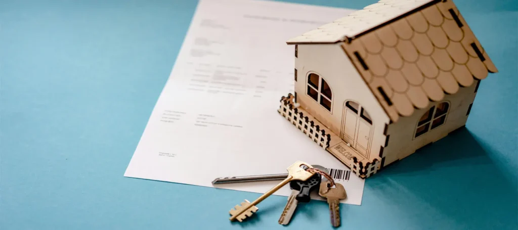 compraventa de viviendas, escritura, llaves y casa de jugete encima de la mesa