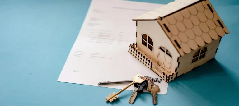 compraventa de viviendas, escritura, llaves y casa de jugete encima de la mesa